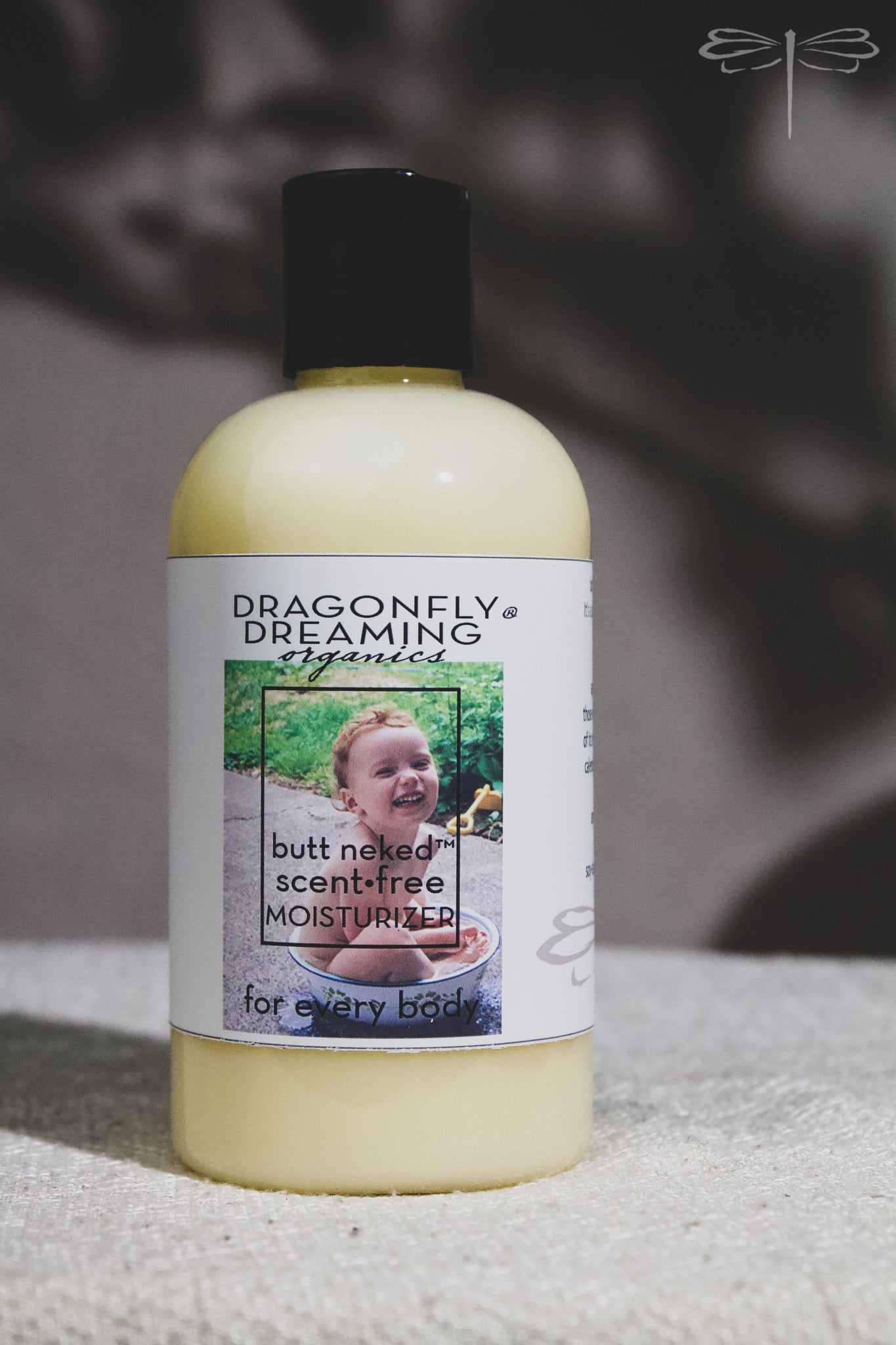 Pictured here, a 250mL bottle of Butt Neked Scent Free Moisturizer by Dragonfly Dreaming Organics